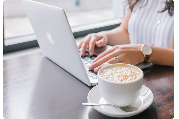 Person typing on laptop with a latte